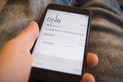 Hånd holder mobil med DNB app.