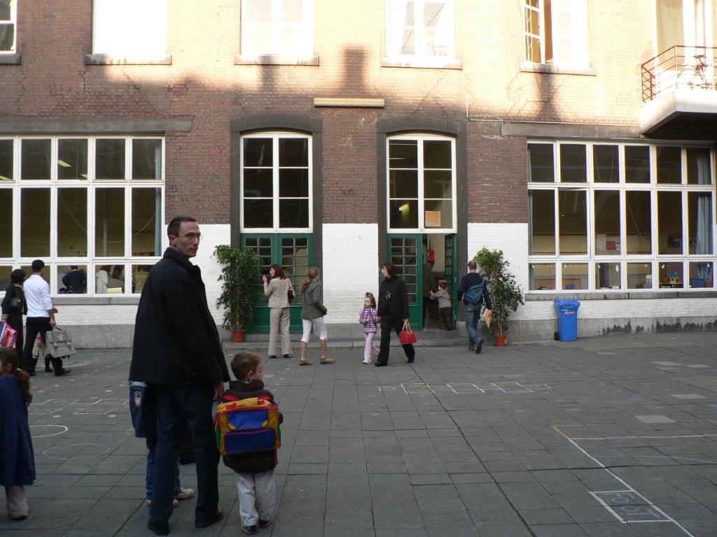 Pappa og gutt går gjennom skolegård mot skolebygning
