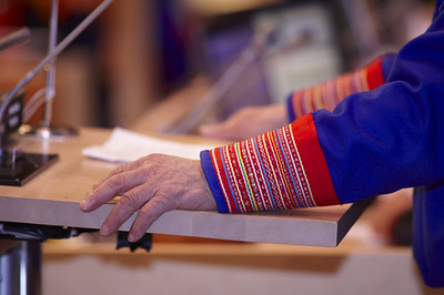 Bildebeskrivelse: Hånd som hviler på en talerstol på Sametinget. Ermet av en samisk kofte.