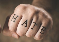 Hånd med budskapet "hate" tatovert på fingrene